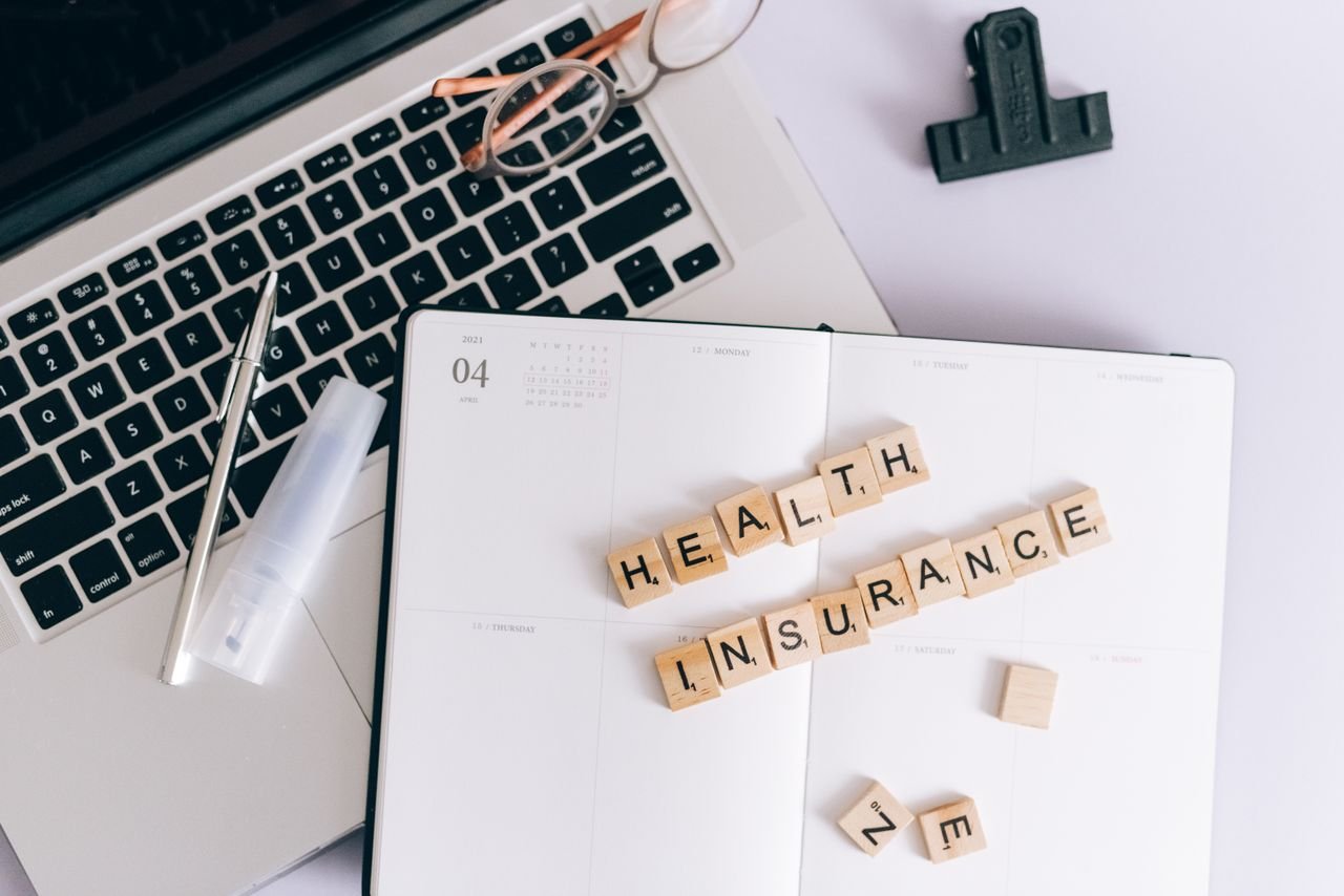 Crafting Captivating Headlines: Your awesome post title goes here Scrabble tiles spelling health insurance on a planner next to a laptop.